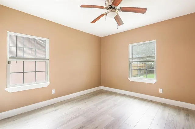 an empty room with windows and fan