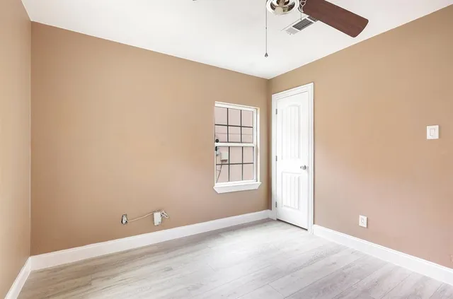an empty room with windows and chandelier fan