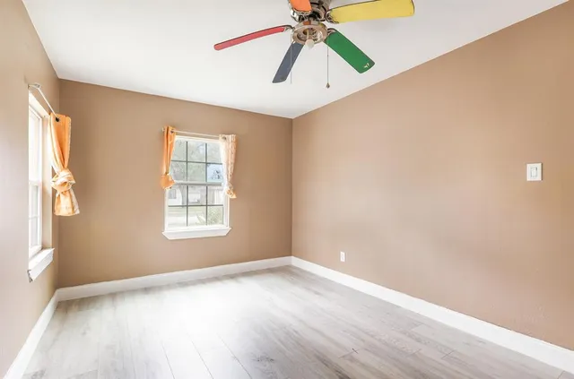 an empty room with windows and fan