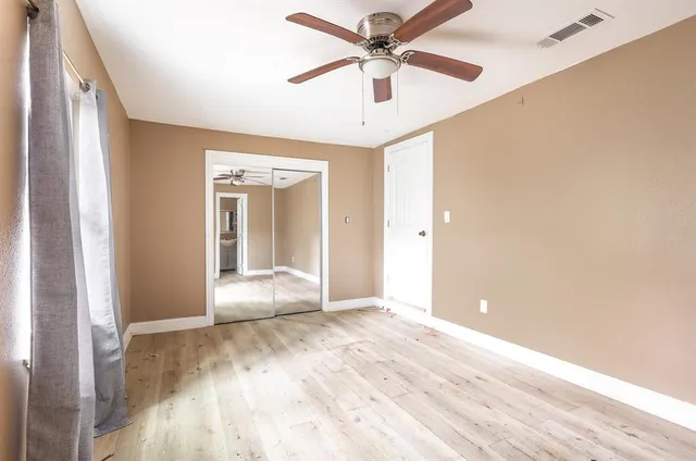 a view of an empty room with window and a ceiling fan