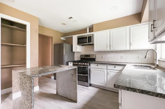 a kitchen with granite countertop a sink stove and refrigerator