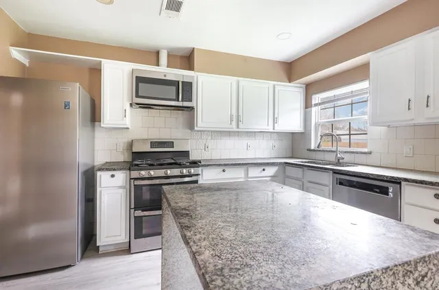 a kitchen with stainless steel appliances granite countertop a stove a sink and a refrigerator