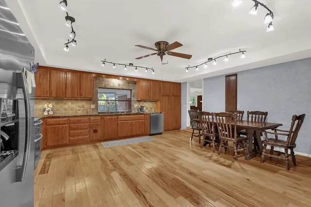 a kitchen with stainless steel appliances kitchen island granite countertop a table chairs sink and cabinets