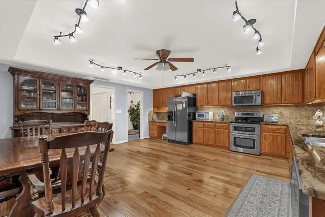 a kitchen with stainless steel appliances granite countertop a stove top oven a sink dishwasher a dining table and chairs with wooden floor