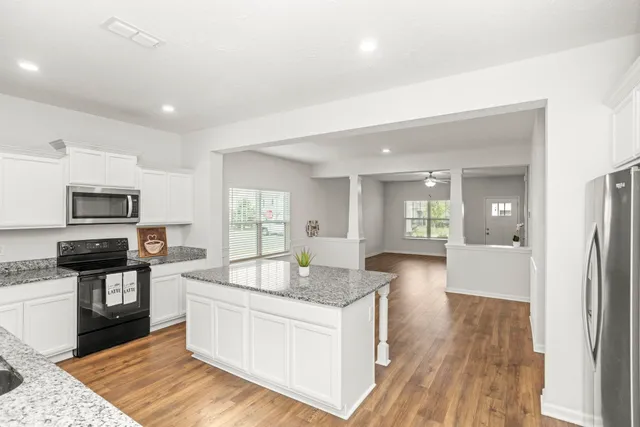 a large white kitchen with granite countertop a sink dishwasher stove and refrigerator