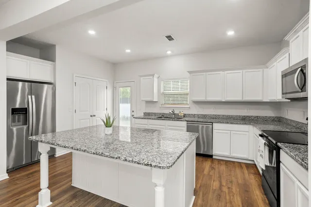 a kitchen with kitchen island granite countertop a stove sink and refrigerator