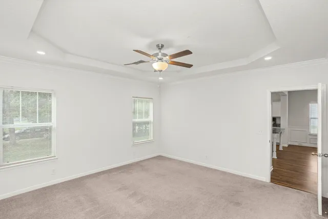 an empty room with windows and ceiling fan