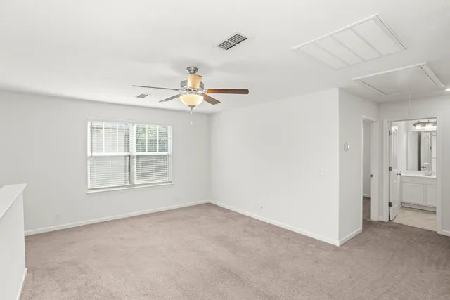 an empty room with windows and fan