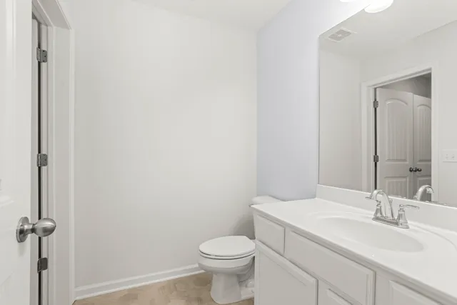 a bathroom with a toilet sink vanity and mirror