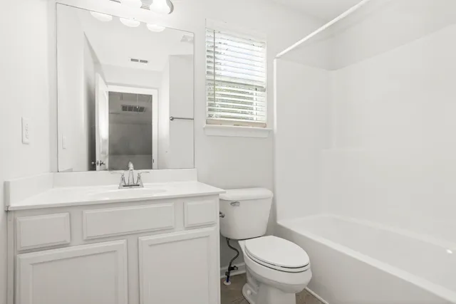 a bathroom with a sink a toilet a mirror and shower