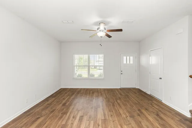 a view of empty room with wooden floor and fan
