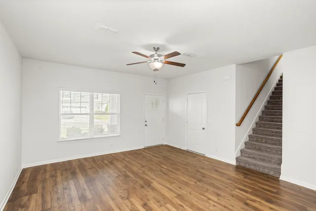 an empty room with wooden floor and ceiling fan