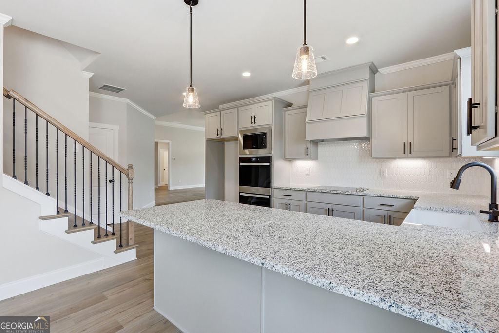720 Youth Jersey Road Loganville, GA 30052 - Photo 11 of 31 a kitchen with stainless steel appliances granite countertop a sink a stove and a wooden floor