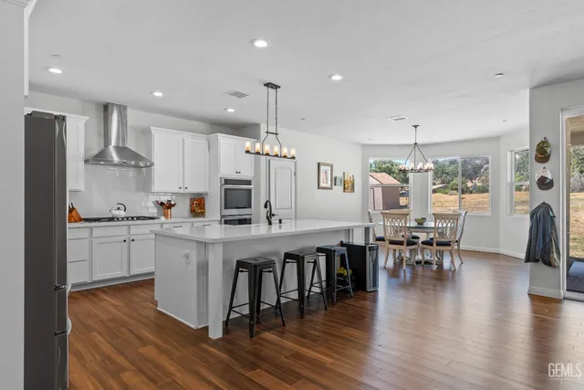 a kitchen with stainless steel appliances granite countertop a table chairs stove microwave and cabinets with wooden floor