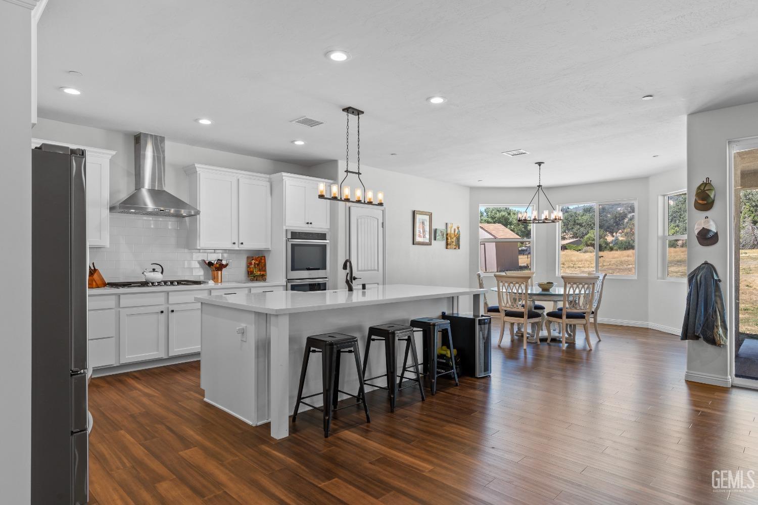 Undisclosed Address Tehachapi, CA 93561 - Photo 9 of 41 a kitchen with stainless steel appliances granite countertop a table chairs stove microwave and cabinets with wooden floor