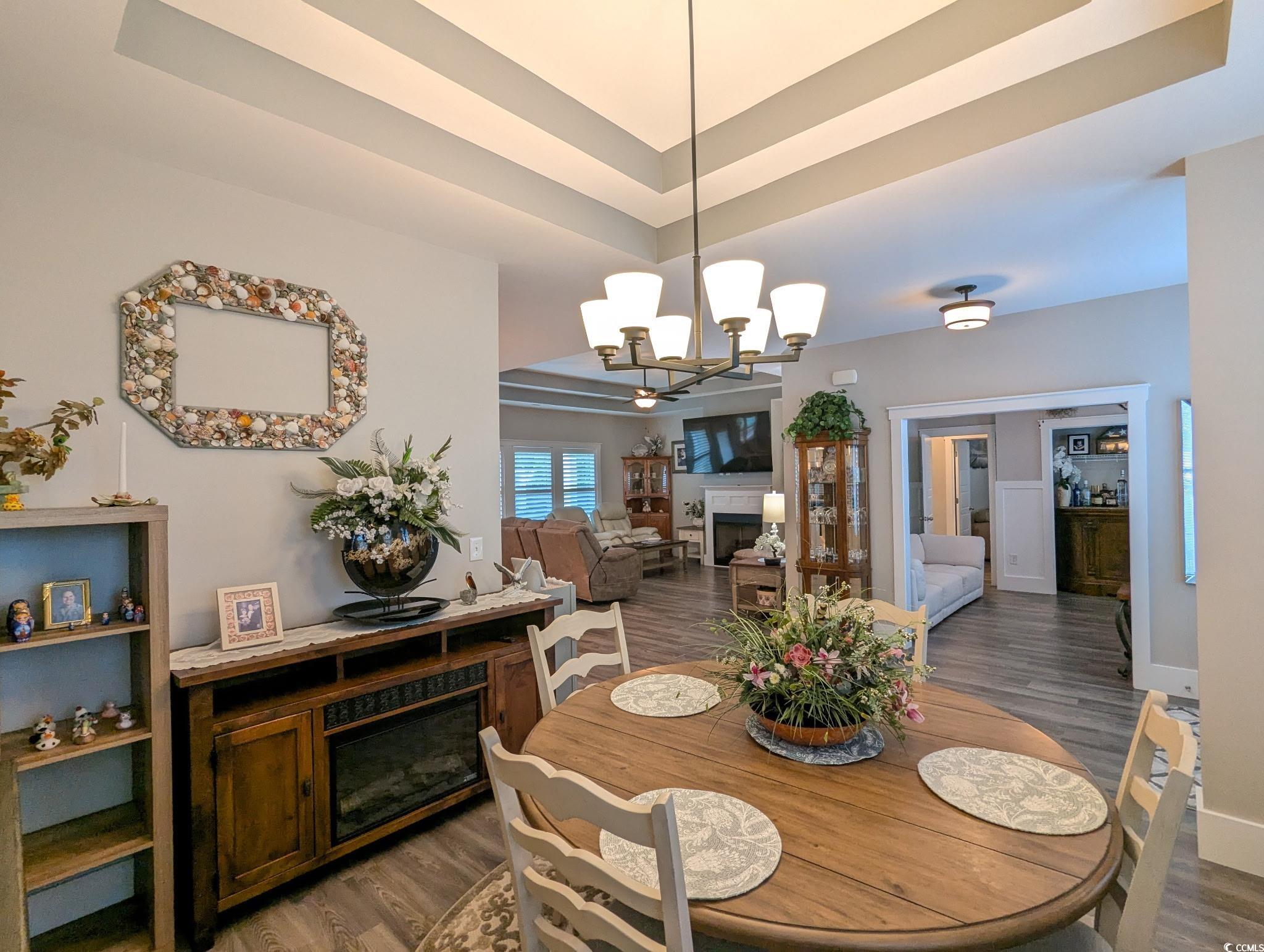 646 Pacific Commons Drive Surfside Beach, SC 29575 - Photo 11 of 40 Dining space featuring a fireplace, a raised ceiling, wood finished floors, and a chandelier