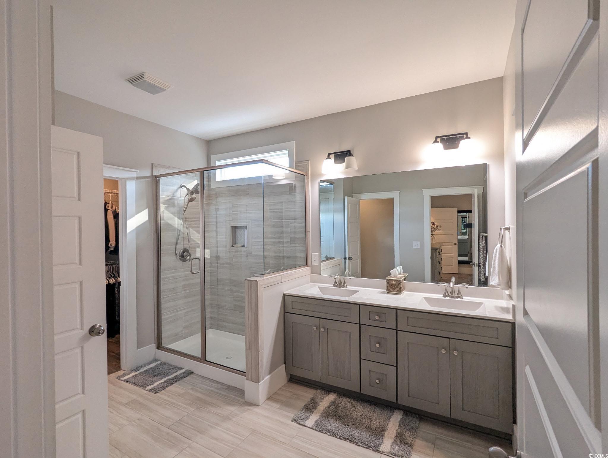 646 Pacific Commons Drive Surfside Beach, SC 29575 - Photo 16 of 40 Full bath featuring a spacious closet, double vanity, a stall shower, and light wood finished floors