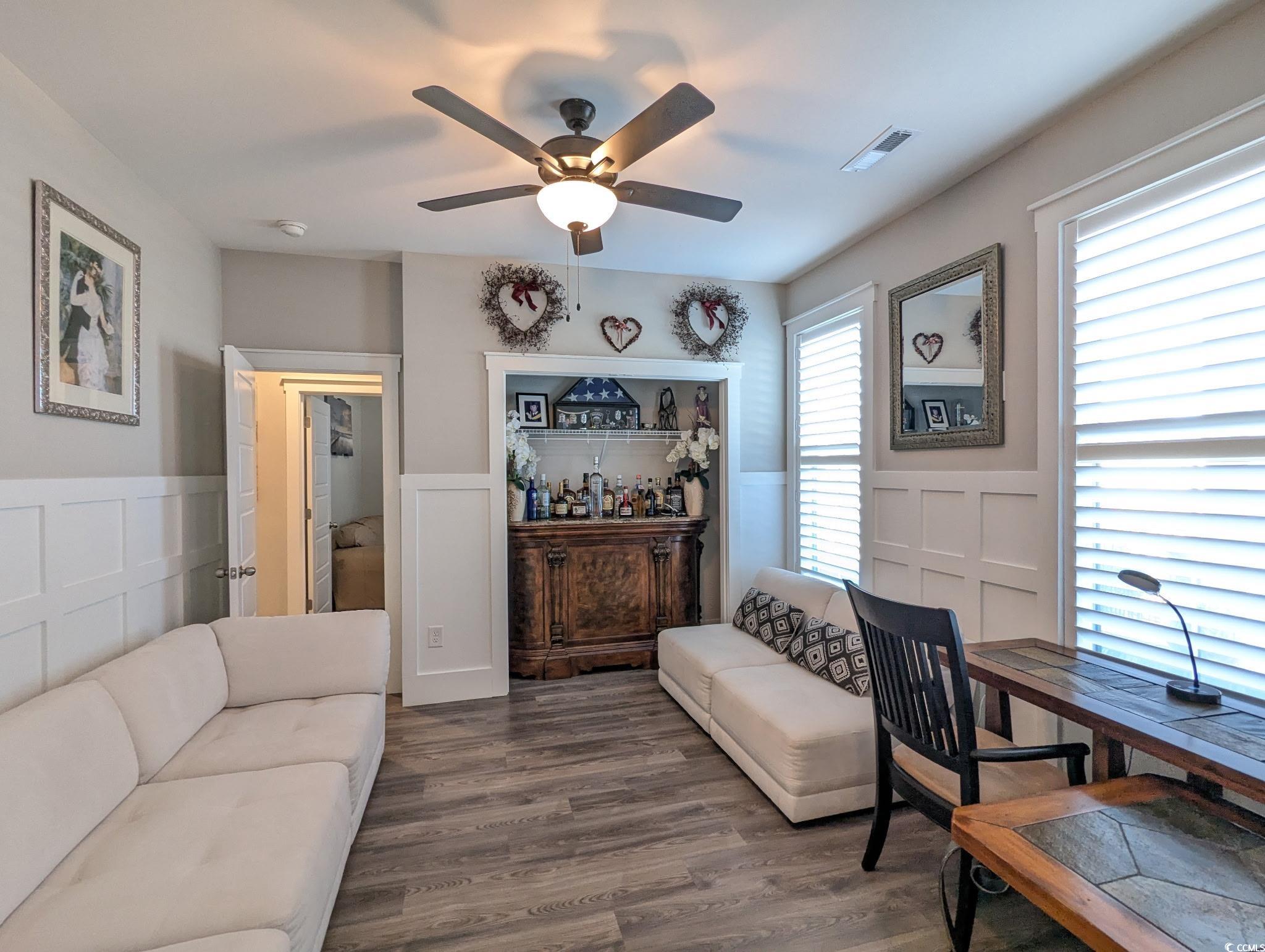 646 Pacific Commons Drive Surfside Beach, SC 29575 - Photo 23 of 40 Living room with wainscoting, a decorative wall, a ceiling fan, and wood finished floors