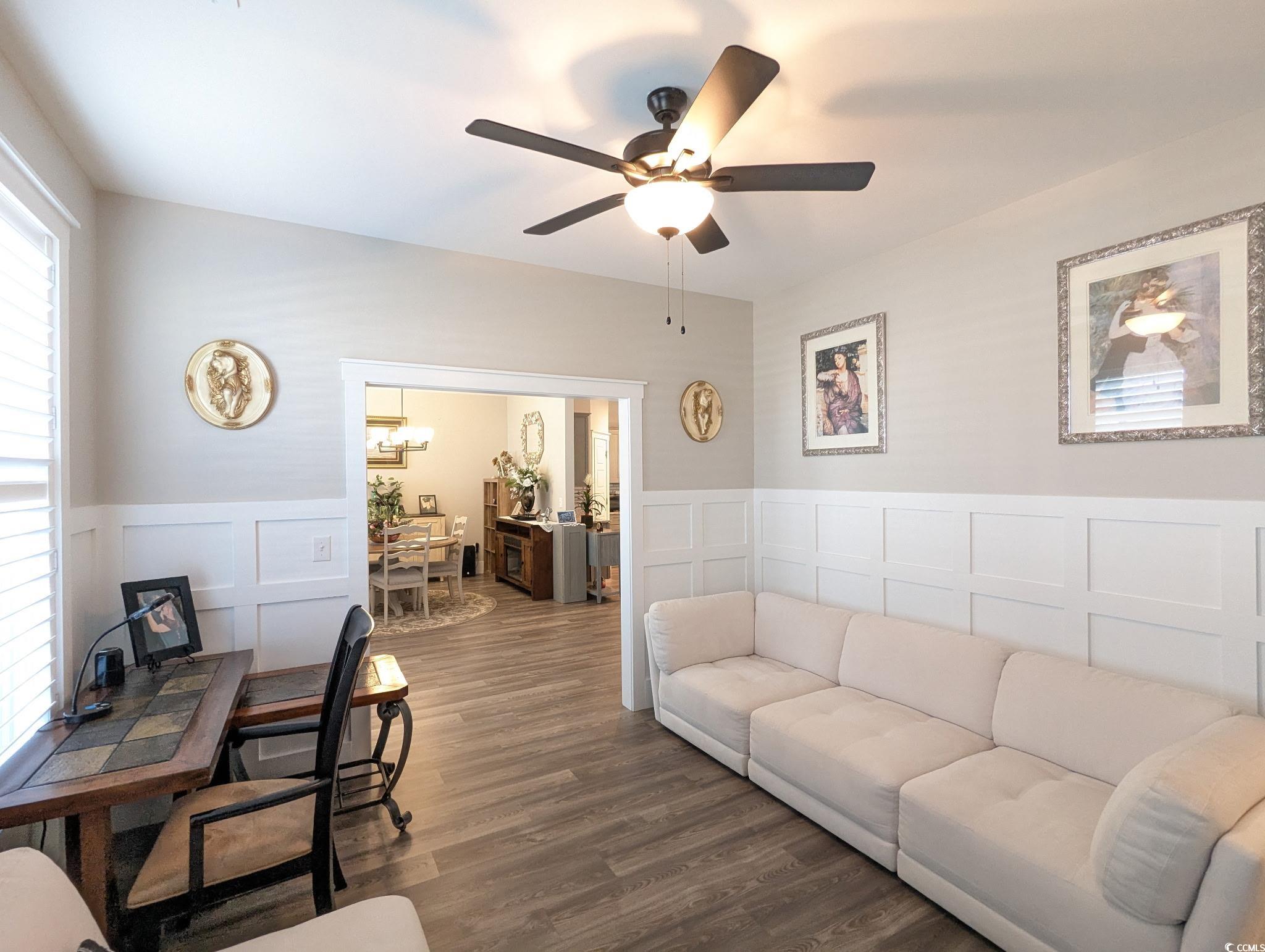 646 Pacific Commons Drive Surfside Beach, SC 29575 - Photo 24 of 40 Living area featuring a decorative wall, wood finished floors, ceiling fan, and wainscoting