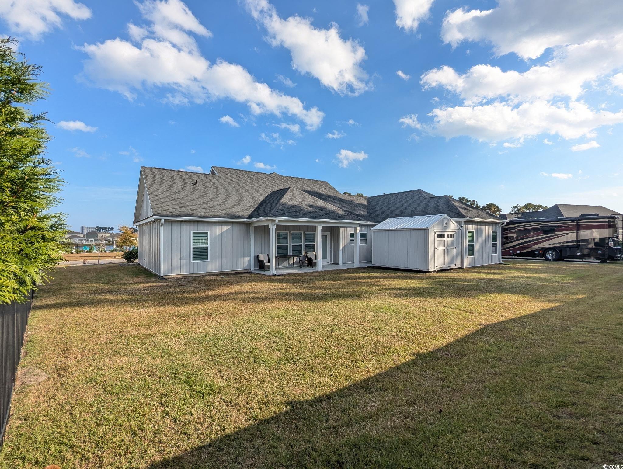 646 Pacific Commons Drive Surfside Beach, SC 29575 - Photo 33 of 40 Back of property featuring a patio, a yard, an outdoor structure, and roof with shingles