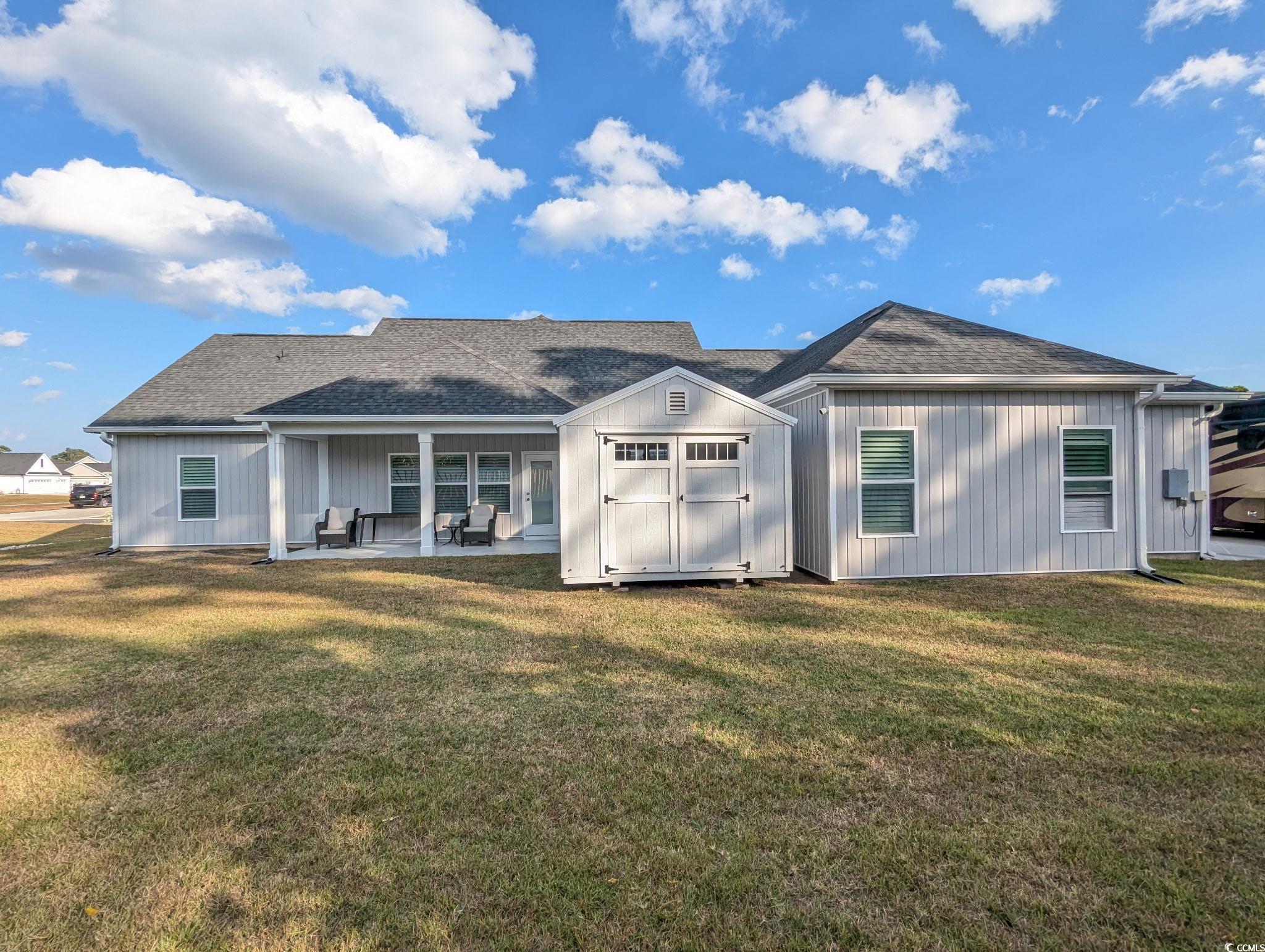 646 Pacific Commons Drive Surfside Beach, SC 29575 - Photo 34 of 40 Rear view of house featuring a patio area, a shed, a lawn, and a shingled roof