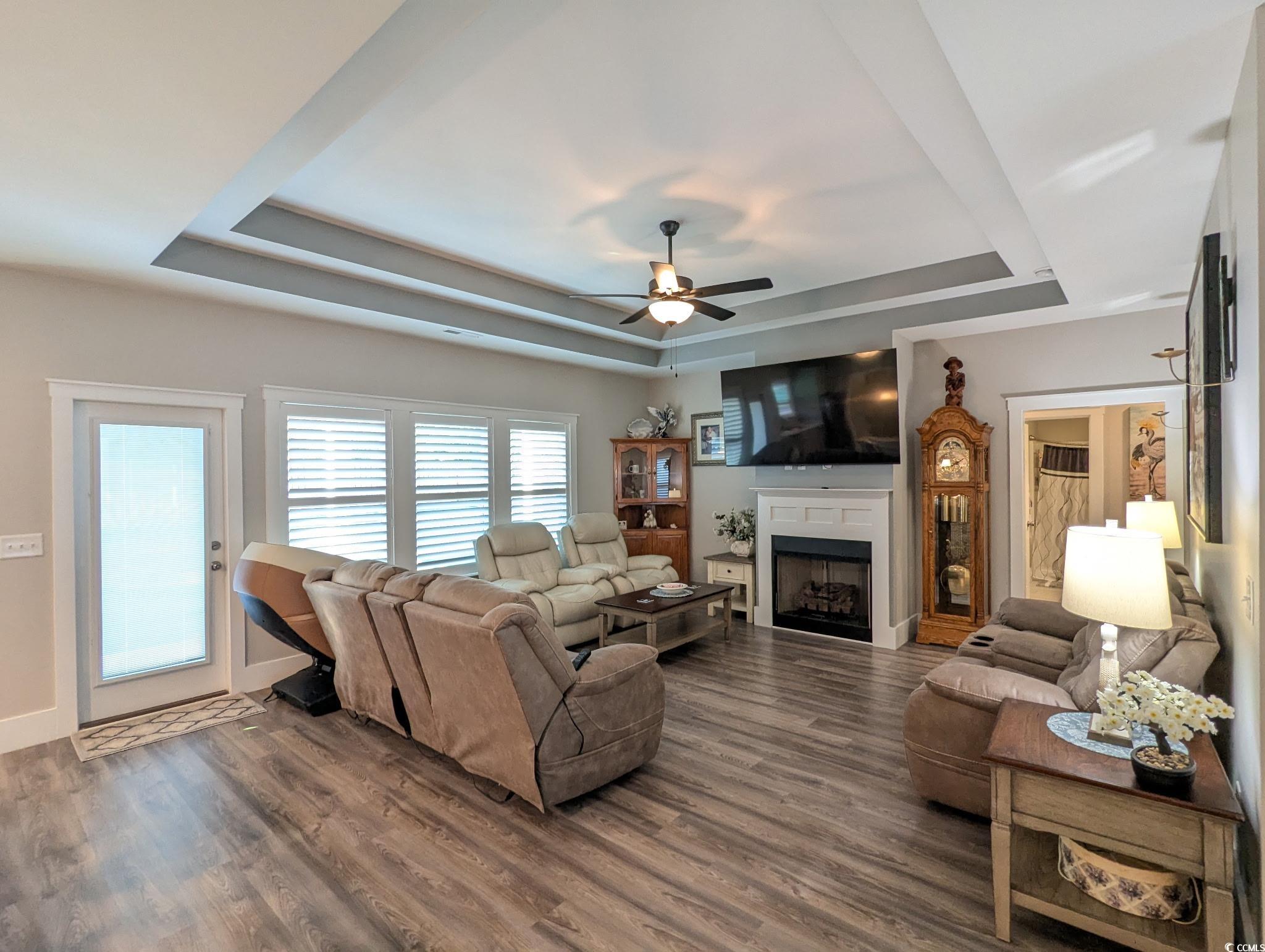 646 Pacific Commons Drive Surfside Beach, SC 29575 - Photo 6 of 40 Living room with a tray ceiling, a fireplace, wood finished floors, and a ceiling fan