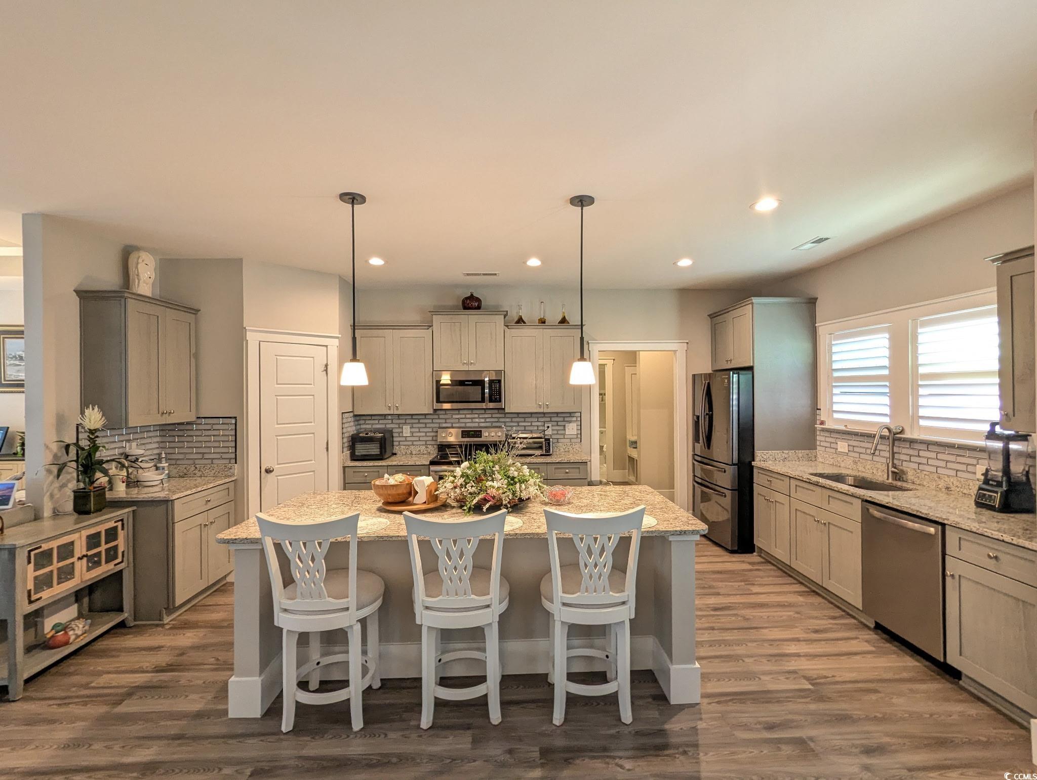 646 Pacific Commons Drive Surfside Beach, SC 29575 - Photo 9 of 40 Kitchen with gray cabinets, decorative light fixtures, a breakfast bar, appliances with stainless steel finishes, and backsplash