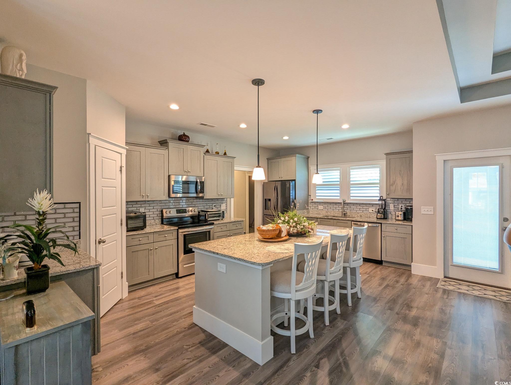 646 Pacific Commons Drive Surfside Beach, SC 29575 - Photo 10 of 40 Kitchen featuring decorative light fixtures, a breakfast bar, decorative backsplash, appliances with stainless steel finishes, and a center island