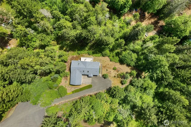 an aerial view of residential house with outdoor space and trees all around