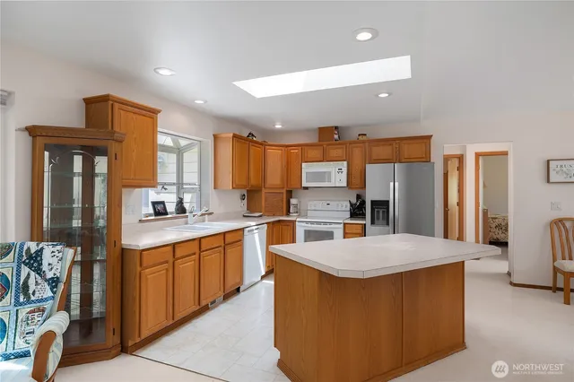 a kitchen with stainless steel appliances kitchen island granite countertop a refrigerator a sink a stove and island with wooden floor