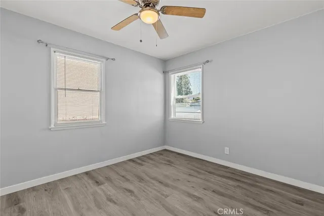 an empty room with wooden floor fan and windows