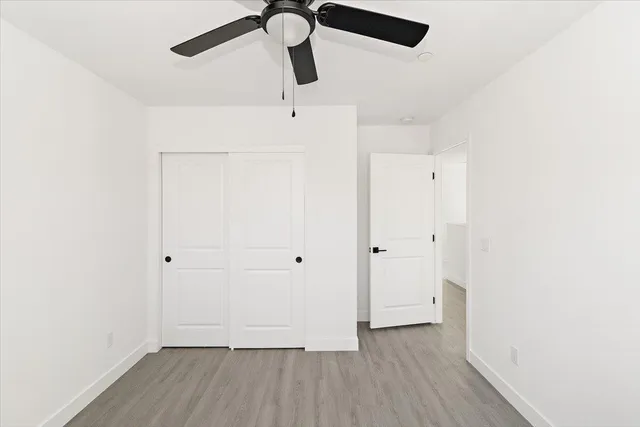 a view of a room with wooden floor closet and ceiling fan