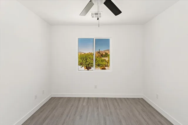 an empty room with a window and ceiling fan