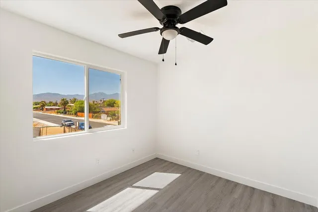 an empty room with a window and a ceiling fan