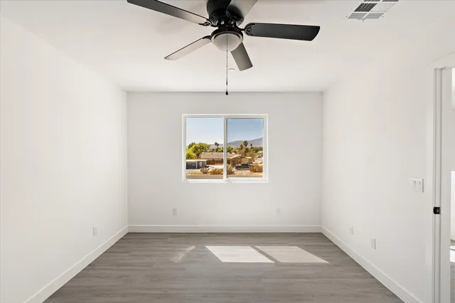 an empty room with a window and a ceiling fan
