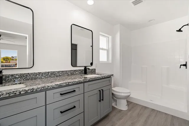 a bathroom with a granite countertop sink a toilet and a mirror