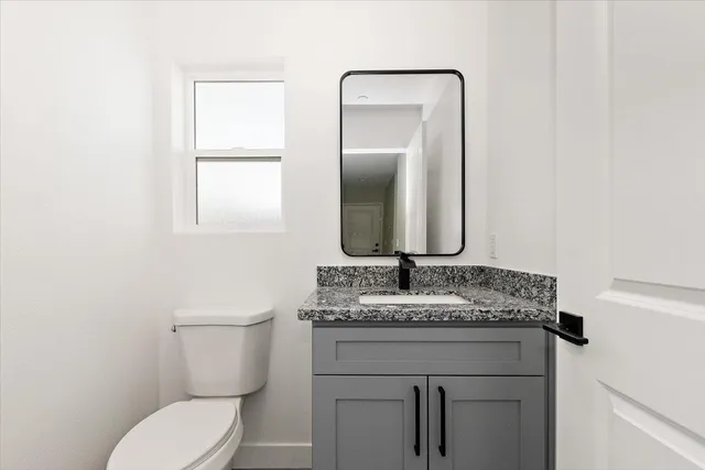 a bathroom with a granite countertop toilet sink and mirror