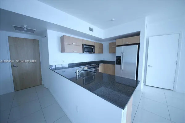 a kitchen with stainless steel appliances granite countertop a sink and a refrigerator