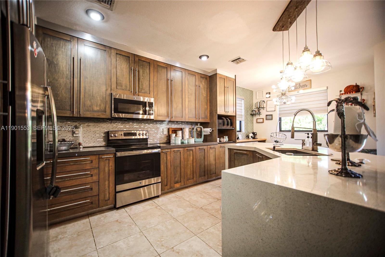 11863 Southwest 233rd Terrace Homestead, FL 33032 - Photo 17 of 77 a kitchen with stainless steel appliances a sink a stove and cabinets