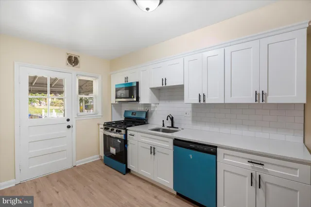 a kitchen with a sink dishwasher a stove and white cabinets