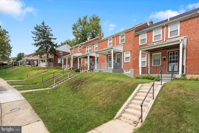 a view of a white house with a big yard and potted plants and a large tree
