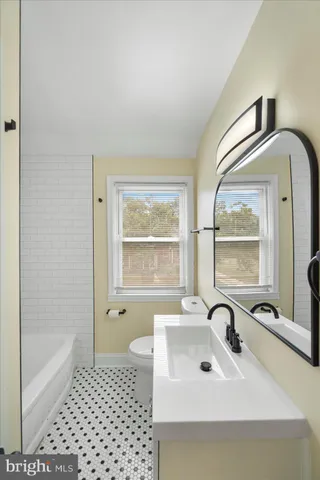 a bathroom with a sink a bathtub and next to a window