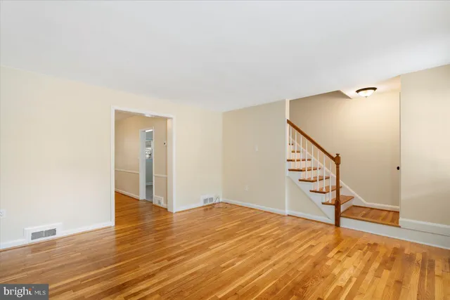 a view of an empty room with wooden floor and stairs