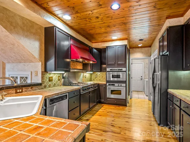 a kitchen with stainless steel appliances granite countertop a stove kitchen island a refrigerator and a stove