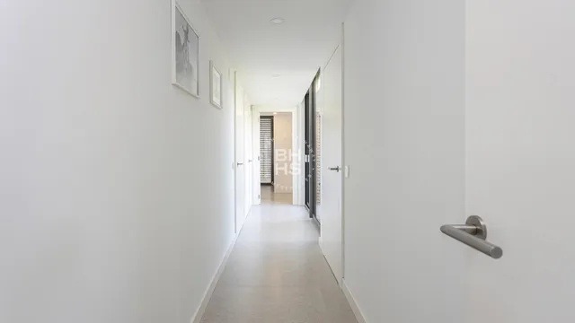 a view of a hallway with wooden floor and a bathroom