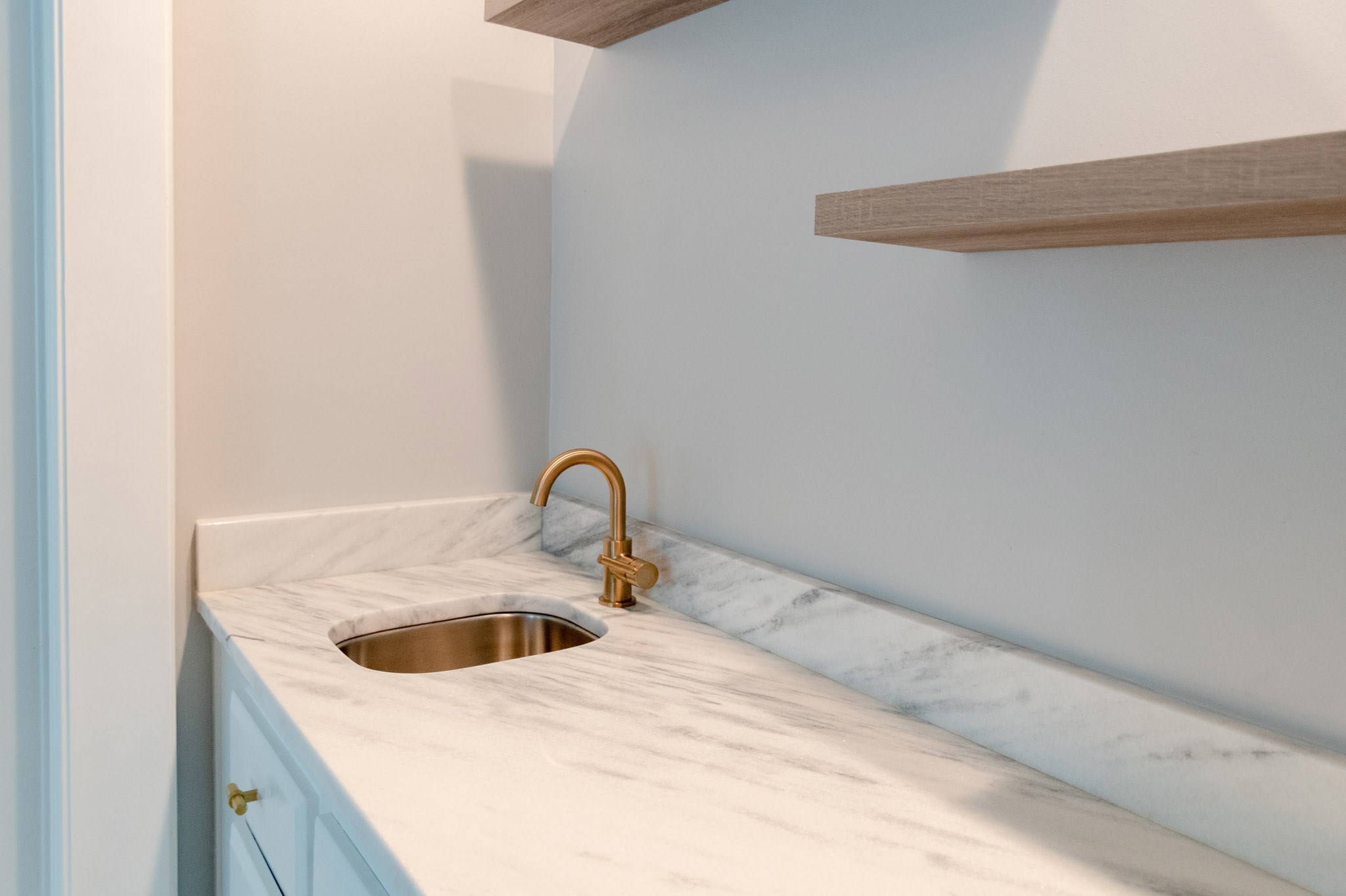 10 Coralvine Court Spring, TX 77380 - Photo 11 of 34 Custom wet bar is upscale with quartz counters, undermount sink with gold faucet, and modern wood floating shelves for storage.