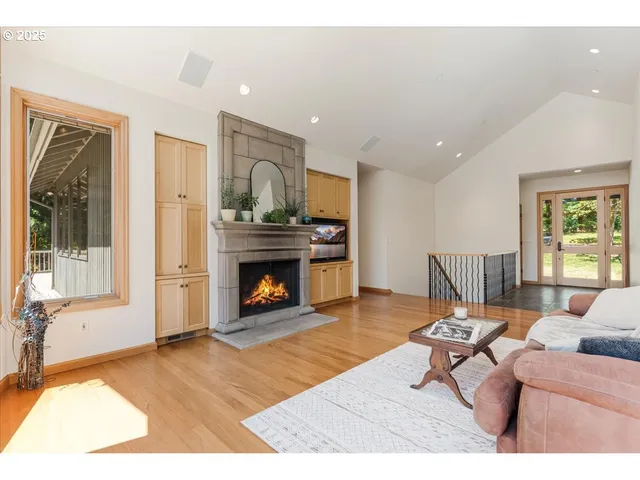 a living room with furniture large windows and wooden floor