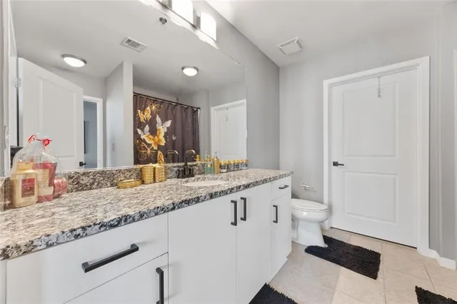 a bathroom with a granite countertop sink mirror and toilet