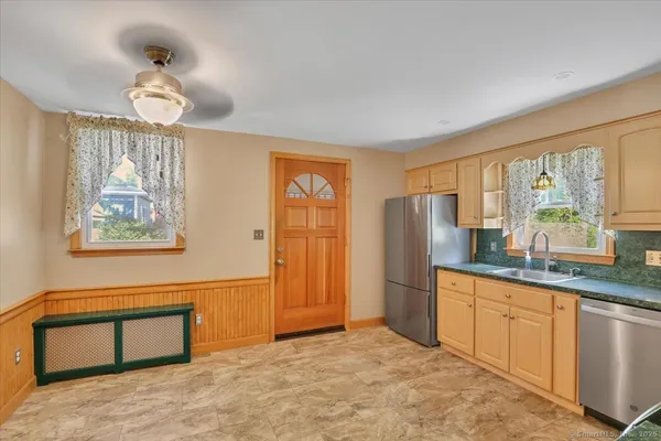 a kitchen with stainless steel appliances granite countertop a refrigerator a sink dishwasher a stove and a dining table with wooden floor