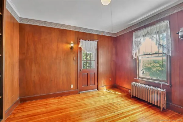 a view of an empty room with window and hardwood floor